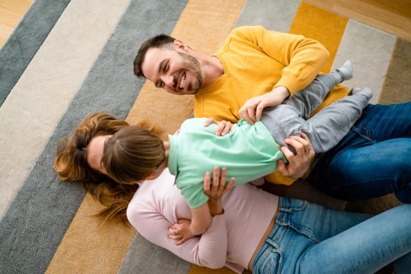 Young happy family being playful and having fun at home. Parenting, childhood, happiness concept.